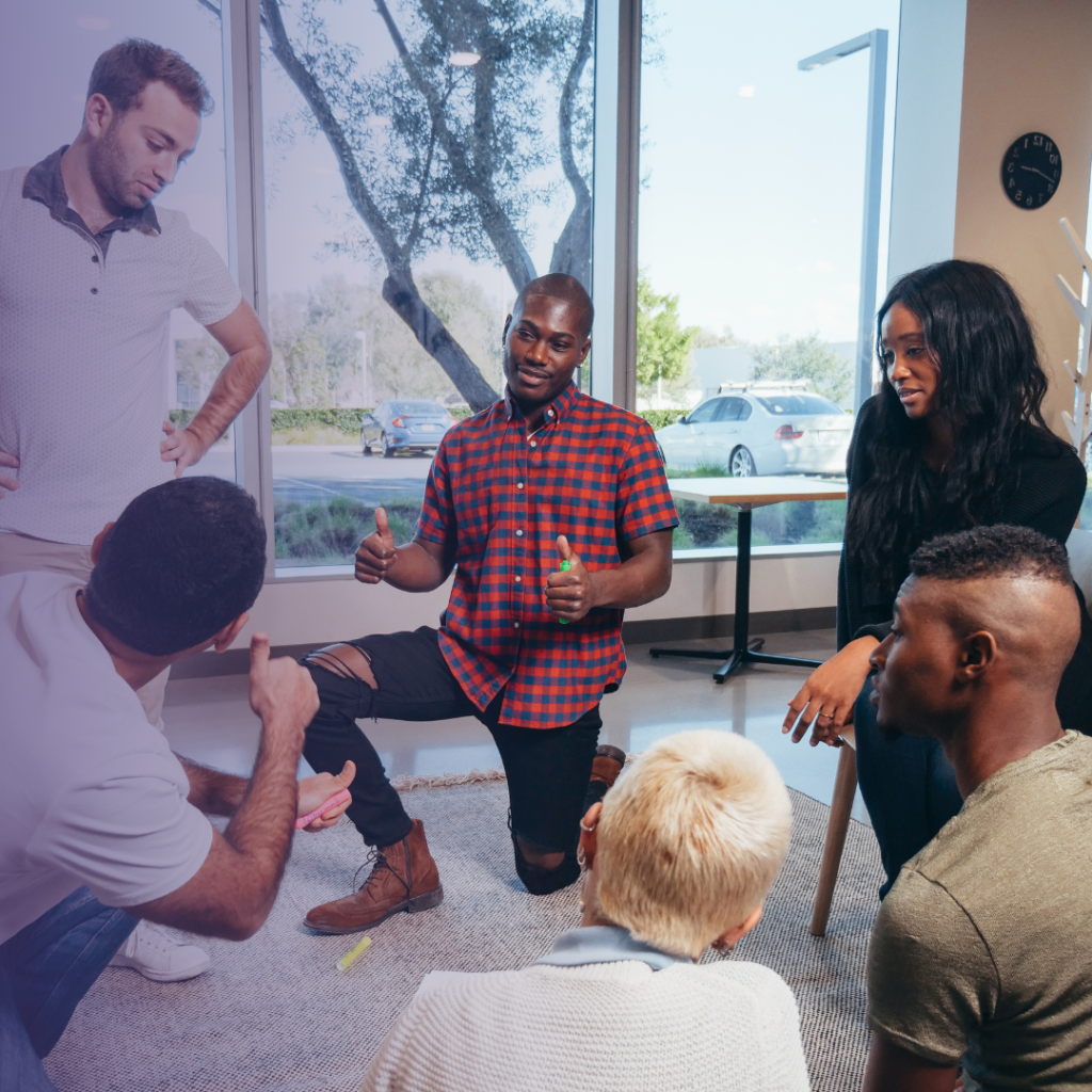 diverse group of workers participating in a workshop. With two men, giving each other a thumbs up